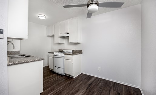 A kitchen with white cabinets and a wood floor.